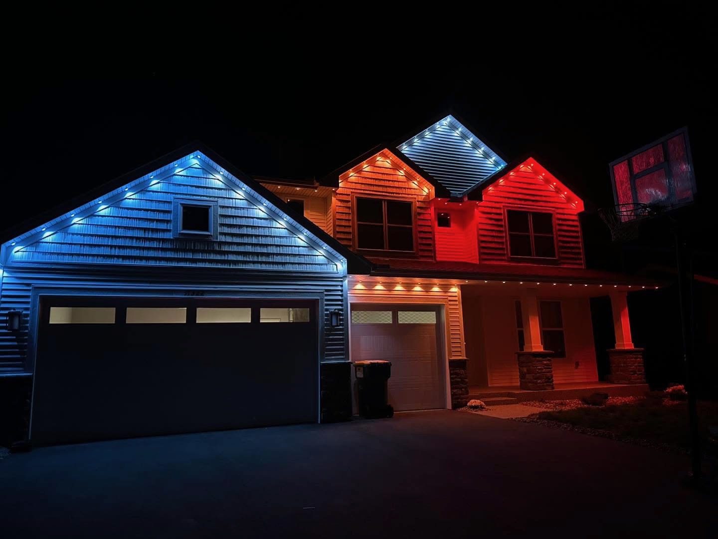 Multi-gable home at night with blue, white, amber and red lighting zones