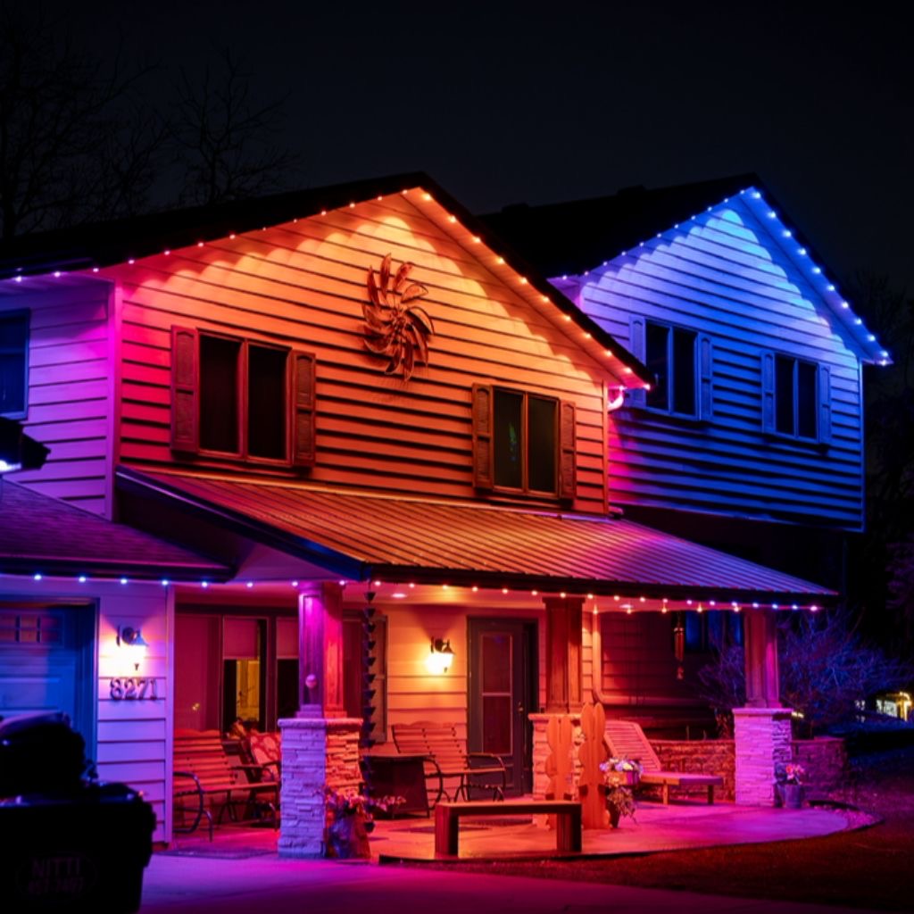 Two-story home at night with blue and orange permanent lights on the gables