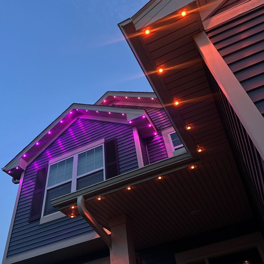Close view of porch and gable soffits lit in warm amber and purple at dusk